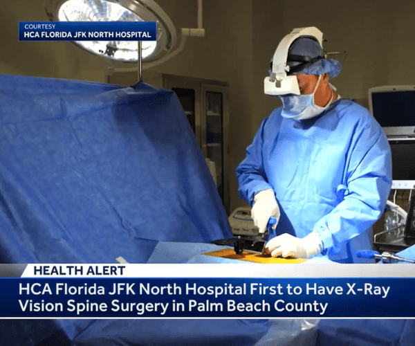 A surgeon wears an AR headset to perform spine surgery