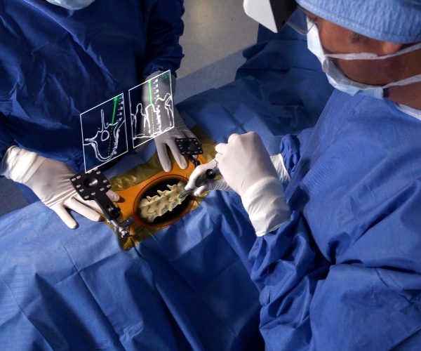 two surgeons operate on spine using augmented reality